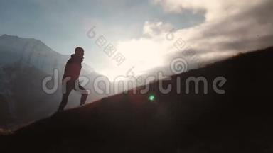 在美丽的日落中，一个人在山的边缘行走，作为一个剪影的史诗镜头的鸟瞰。 剪影